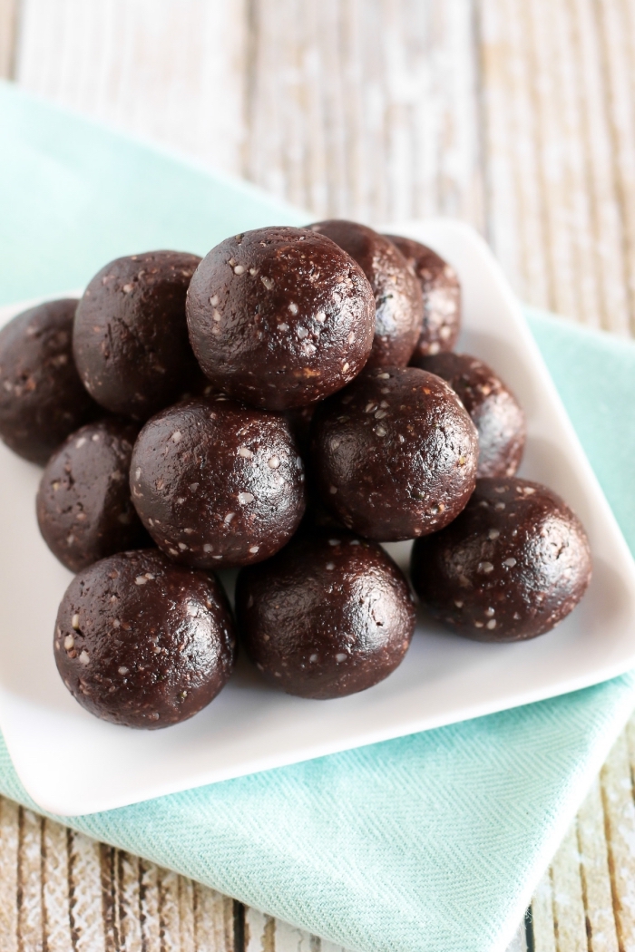 chocolate truffles, arranged in a pyramid, in a white plate, blue cloth, wooden table, no bake energy balls