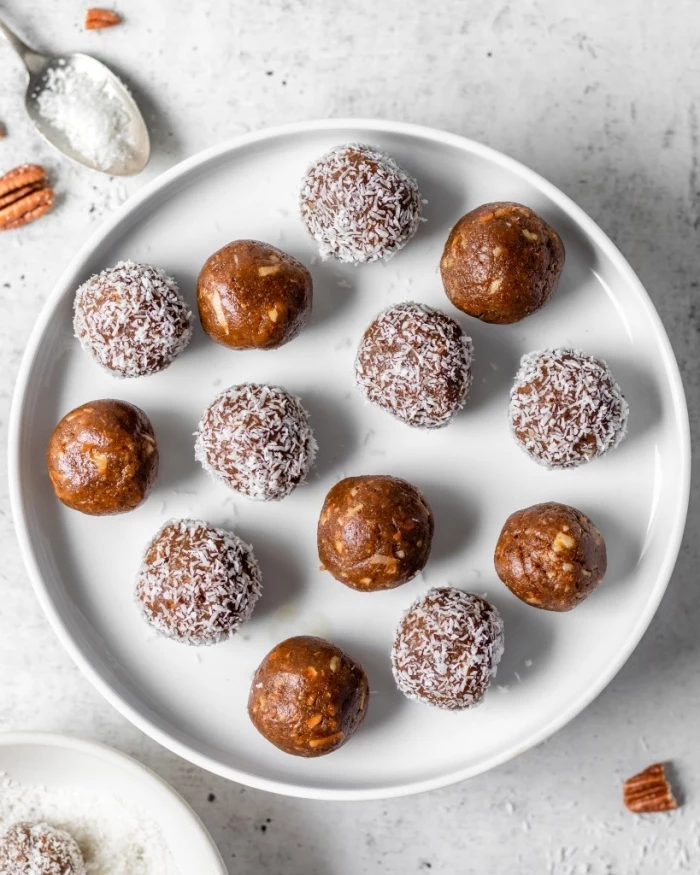 walnuts scattered on the table, no bake energy balls, covered with coconut flakes, white plate