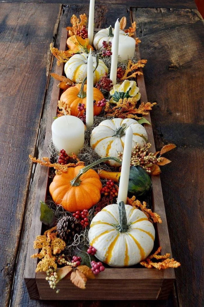 small pumpkins, pine cones, fall leaves, candles inside wooden crate, on wooden table, autumn decor