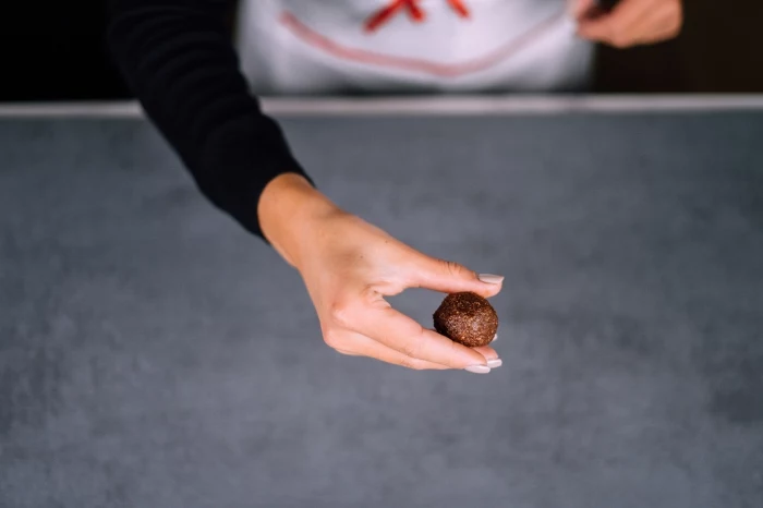 granite countertop, peanut butter protein balls, female hands, with grey nail polish, shaping chocolate into a ball