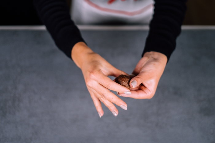 peanut butter protein balls, female hands, with grey nail polish, shaping chocolate mixture, into a ball