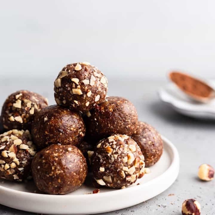 chocolate truffles, with nuts, on white plate, power balls recipe, blurred background