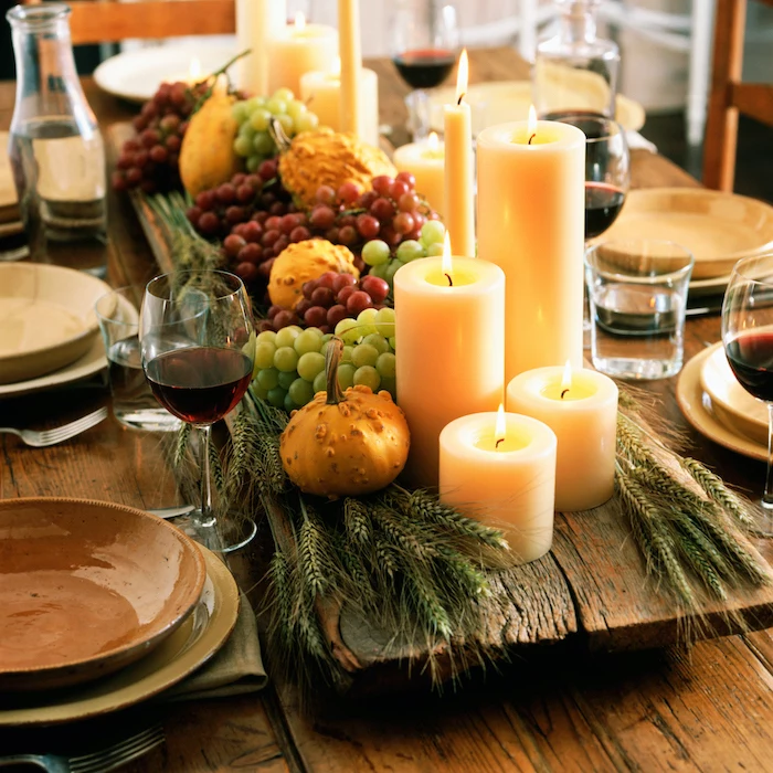 grapes and pumpkins, candles and wheat, on wooden log, outdoor thanksgiving decorations, wooden table, plate setting