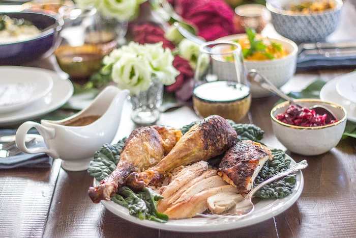 carved turkey, white plates, gravy in a jug, cranberry sauce, roast turkey recipe, wooden table, flower bouquets