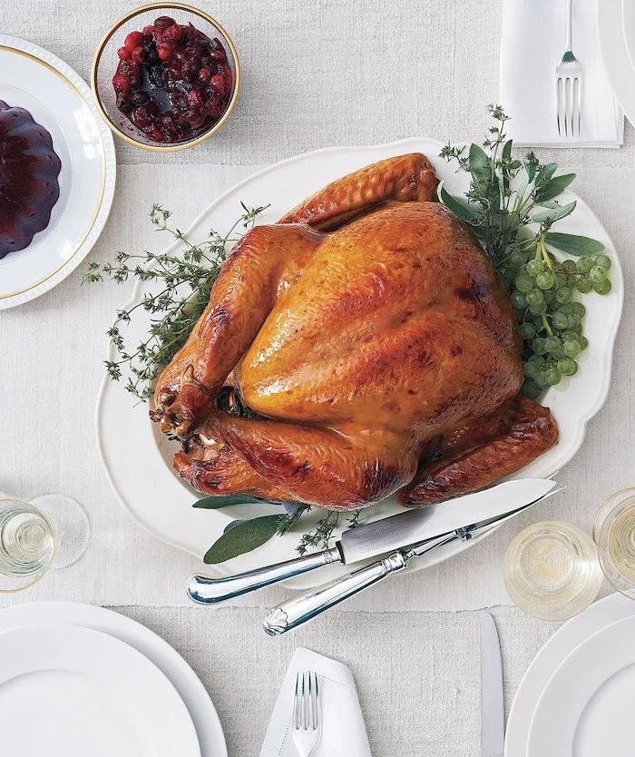 cranberry sauce, white table cloth, roast turkey recipe, fresh herbs, on the side, white plate, wine glasses