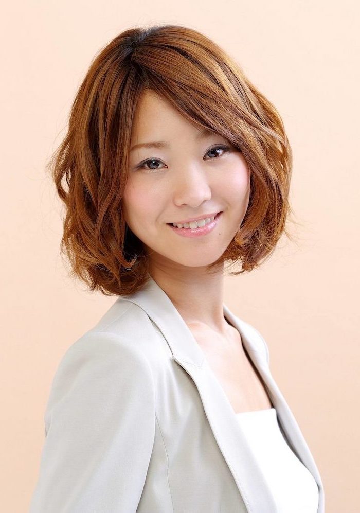 woman smiling, brown wavy hair with side swept bangs, medium length layered hair, wearing grey blazer, white top