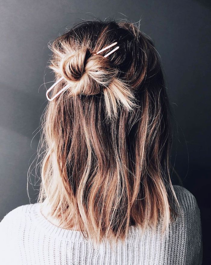 shoulder length bob, woman with balayage blonde hair, half up in messy bun, wearing white sweater