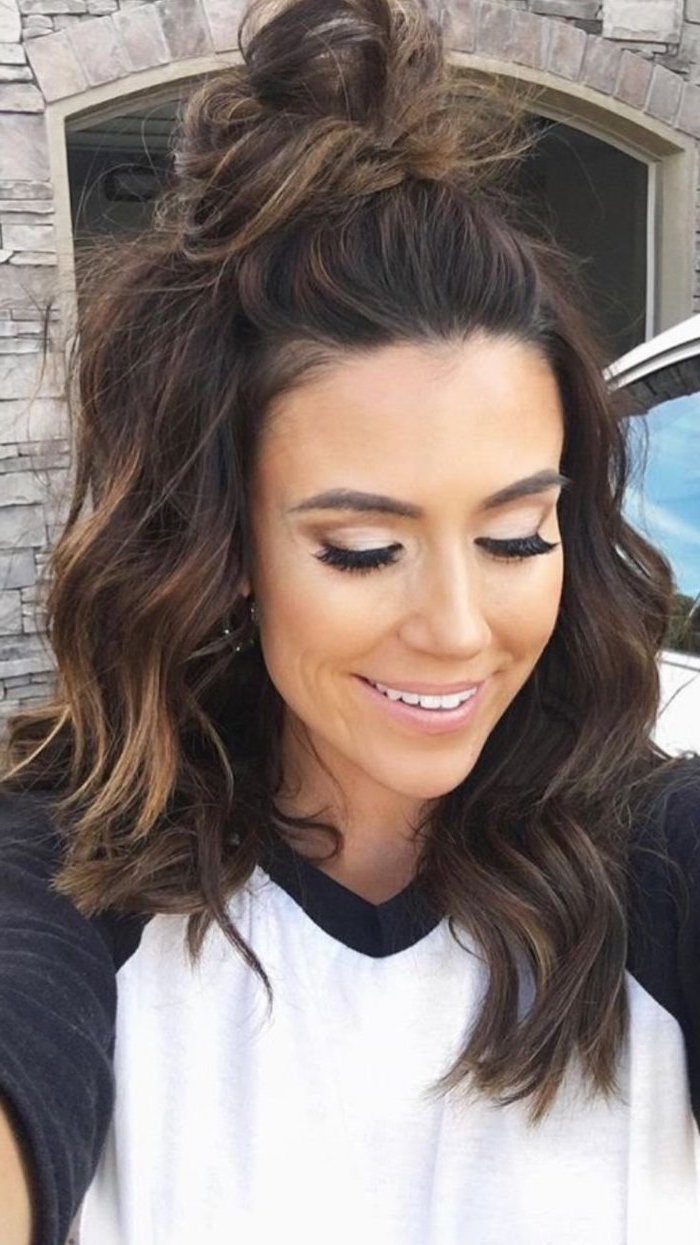 woman smiling, brown hair half up in a messy bun, shoulder length bob, wearing black and white blouse