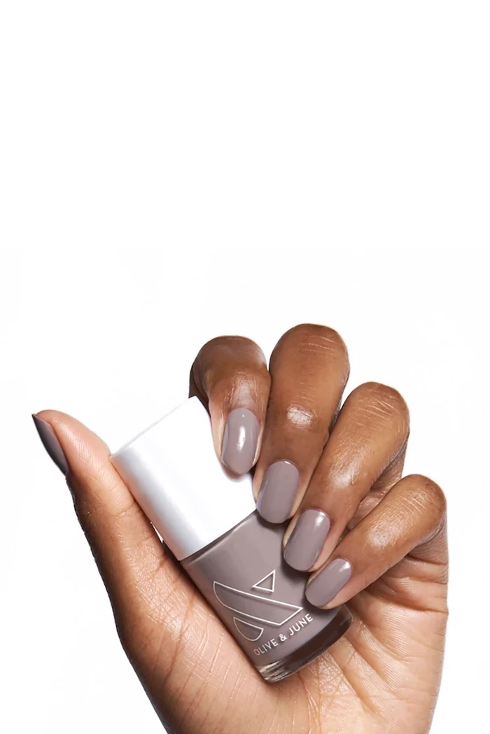 female hand, holding a grey, nail polish bottle, white background, squoval nails, cute nail colors
