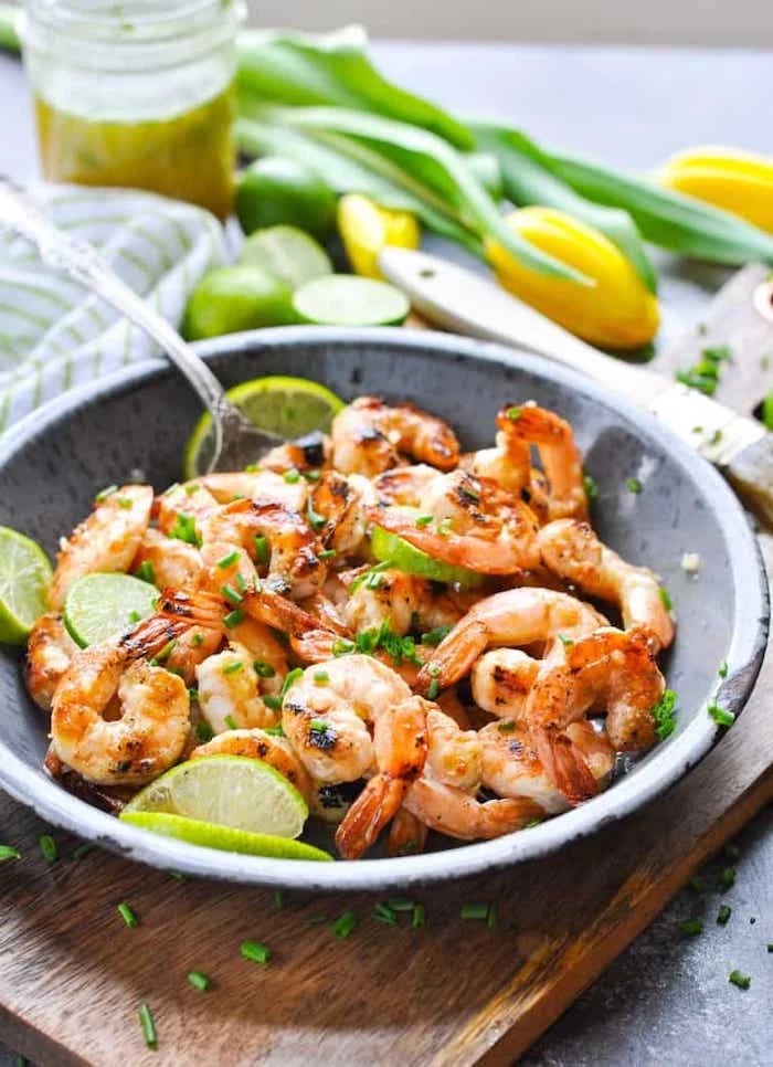 shrimp with lime slices, weight loss meal plan, ceramic bowl, wooden cutting board, silver spoon, chives on top