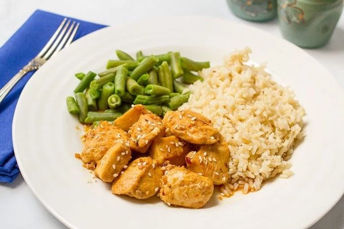 rice and beans, honey garlic chicken, in white plate, dinner ideas for tonight, blue napkin, fork on top, white table