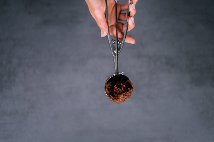 granite countertop, energy balls, female hand, with grey nail polish, holding and ice cream scoop, with chocolate mixture