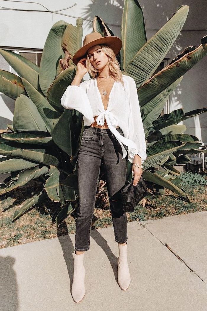 woman wearing a hat, jeans and white blouse, hairstyles for medium length hair, blonde wavy hair, large palm tree in the background