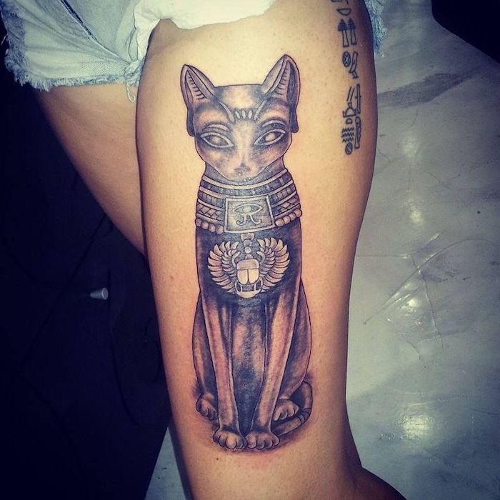leg tattoo ideas, sacred egyptian cat, denim shorts, white floor