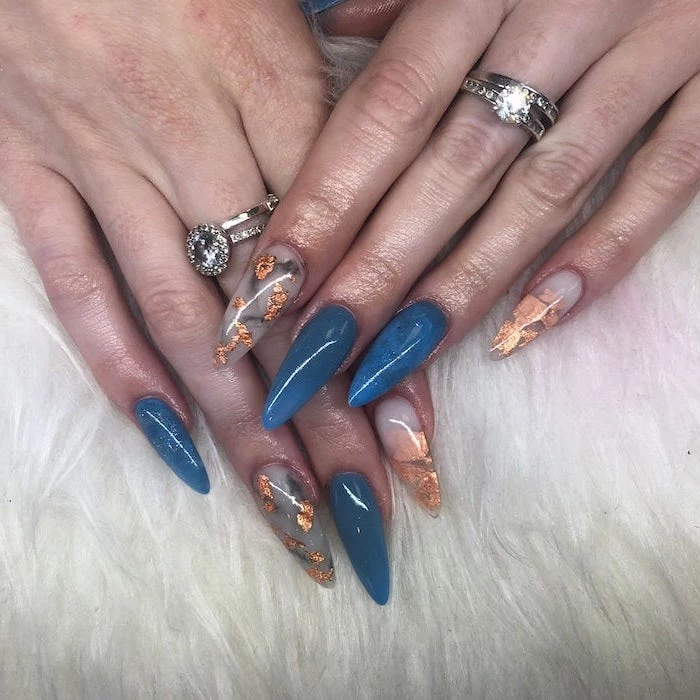 long stiletto nails, blue nail polish, gold glitter, nail decorations, autumn nails, silver rings