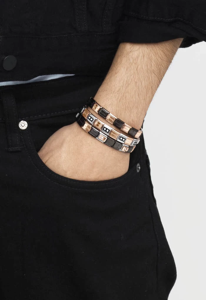 christmas gift ideas, man with black jeans, black denim jacket, hand in pocket, three bracelets