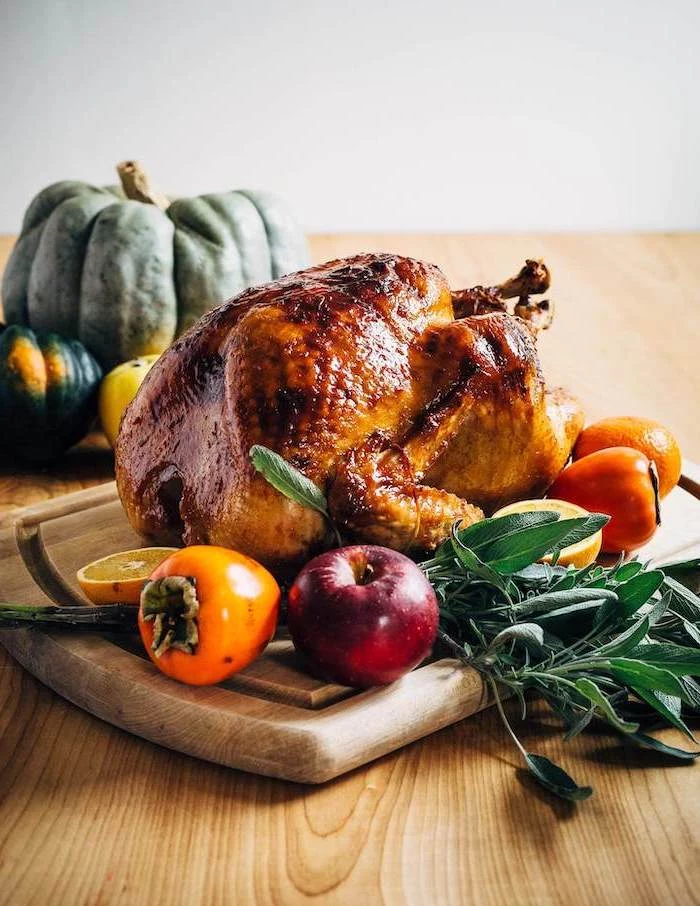 roasted turkey, thanksgiving turkey recipe, apples and tangerines, fresh herbs, wooden board, wooden table