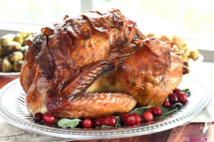 how to cook a turkey, silver tray, roasted turkey inside, with cranberries, fresh herbs, on the side