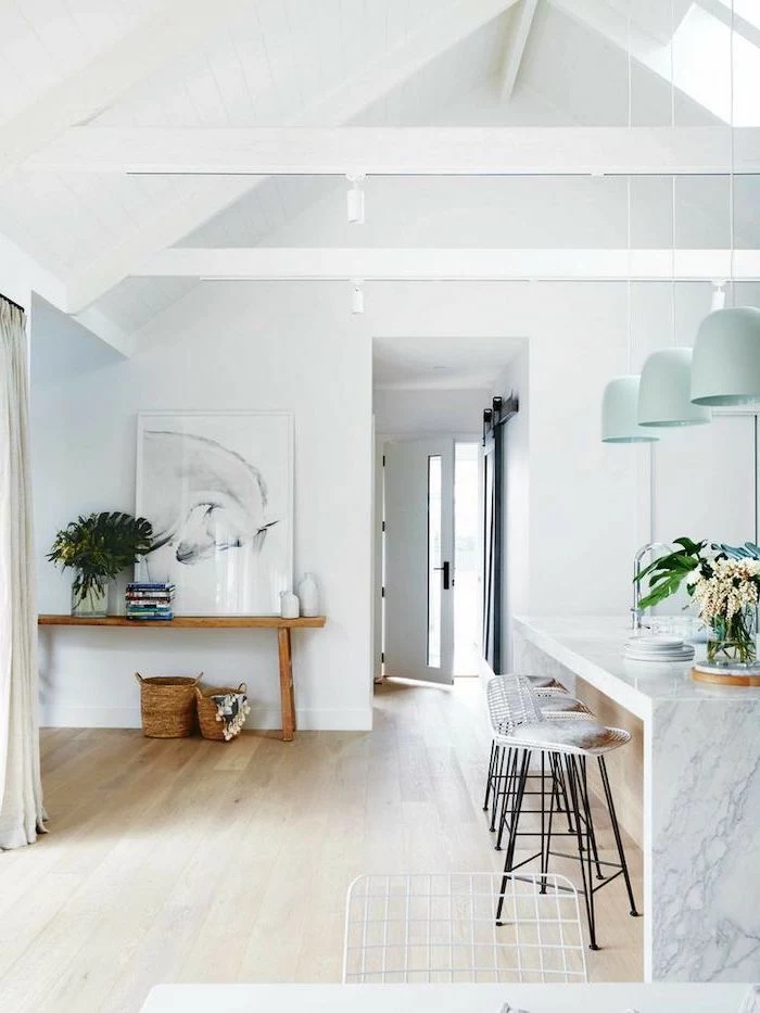 hanging blue lamps, over marble kitchen island, bar stools, what is a vaulted ceiling, wooden floor, white walls