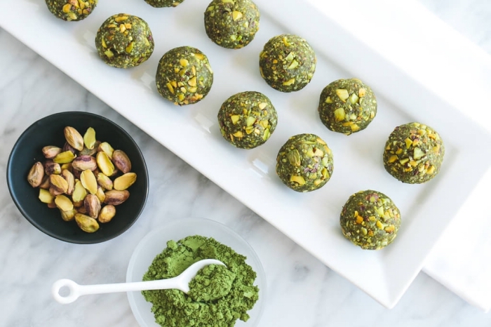 matcha powder, pistachio nuts, in two bowls, energy bites recipe, arranged on white plate, marble countertop