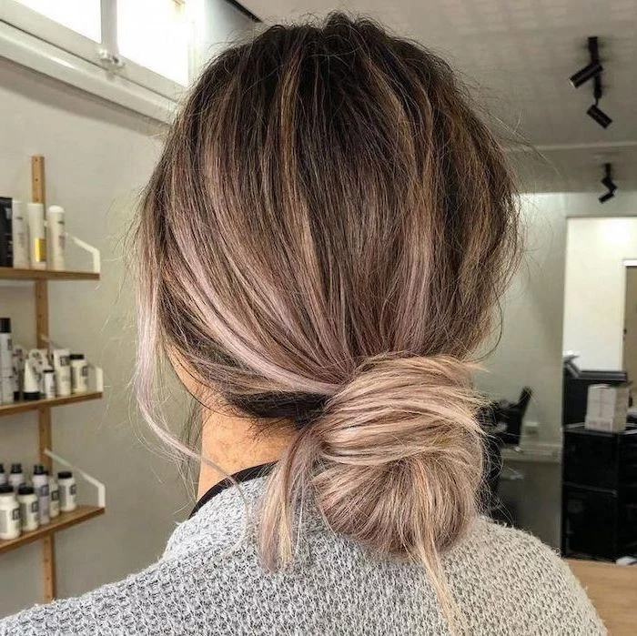 shoulder length hairstyles, balayage blonde hair, in a low chignon, woman wearing grey sweater