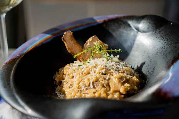 mushroom risotto recipe, placed in black bowl, topped with parmesan and fresh thyme