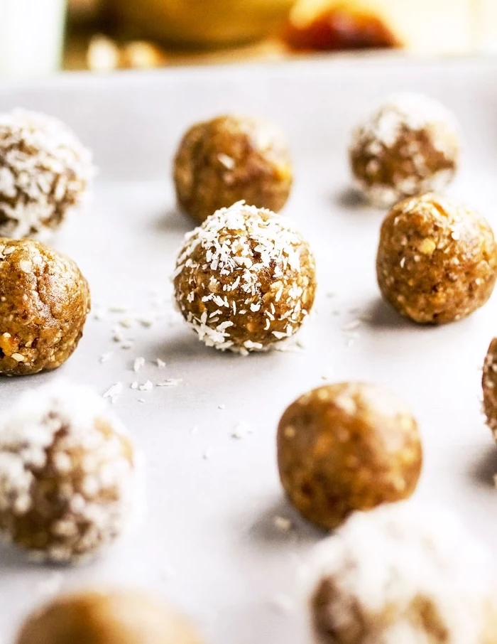 date energy balls, peanut butter bites, covered with coconut flakes, on baking paper