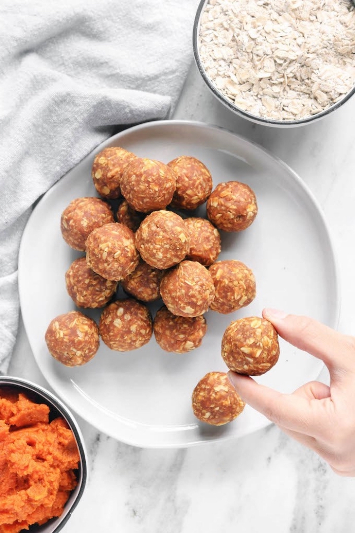 peanut butter oat balls, oatmeal in a bowl, squashed carrots in a bowl, white plate, marble countertop