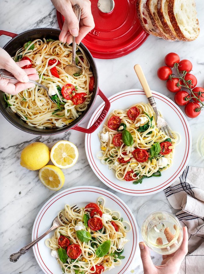 pot full of pasta, pasta in two white plates, with tomatoes and mozzarella, basil leaves for garnish, easy dinner ideas