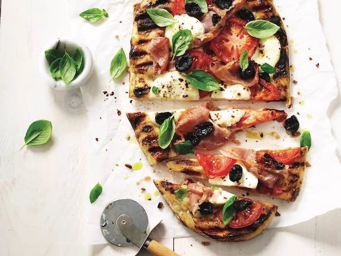grilled pizza, with mozzarella, tomatoes and olives, basil leaves on top, what to make for dinner tonight, cut into pieces