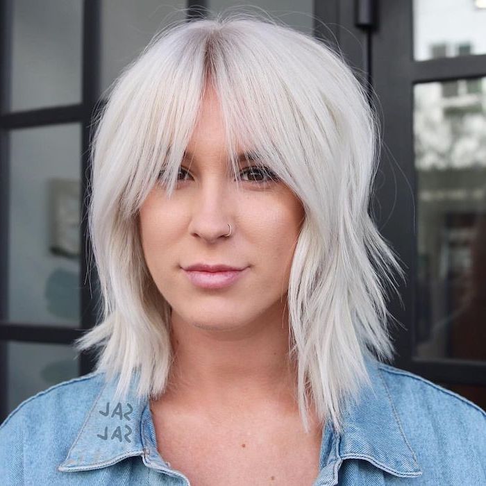 woman with platinum blonde hair with bangs, wearing denim jacket, medium length haircuts for women, nose ring