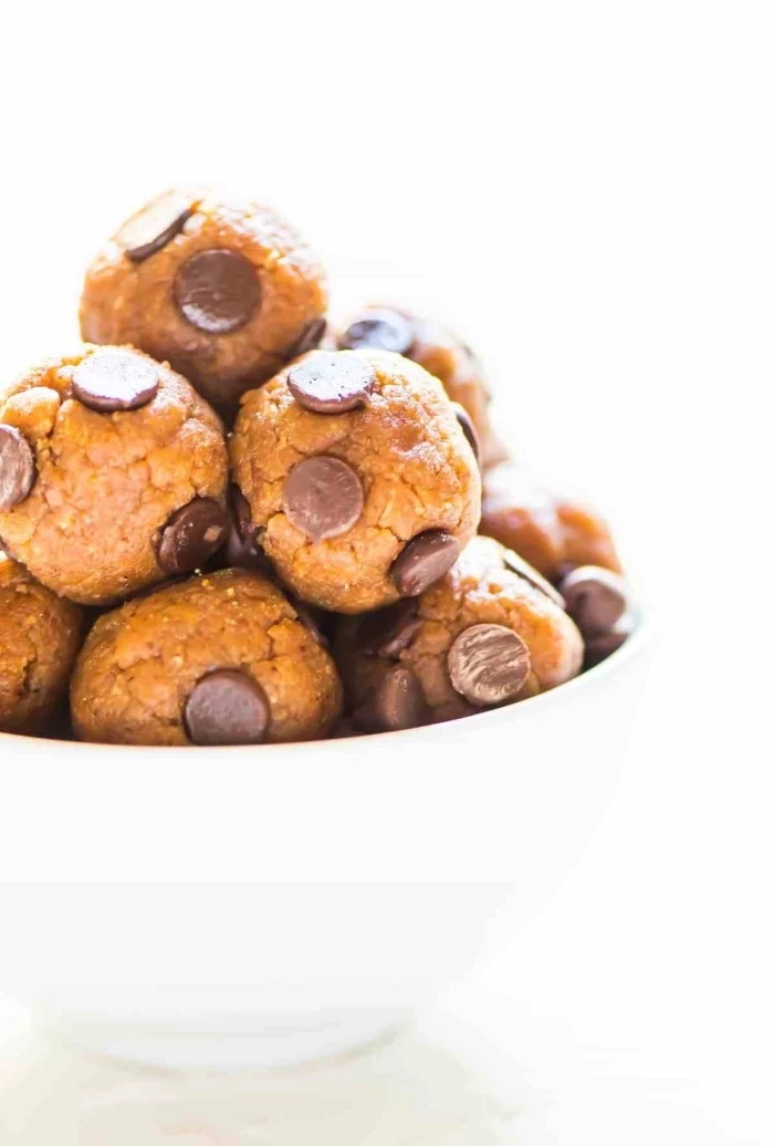 chocolate peanut butter protein balls, with chocolate chips, in a white bowl, white background