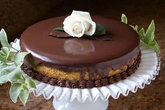 best thanksgiving desserts, pumpkin cake, chocolate glaze, on white cake stand, white rose on top