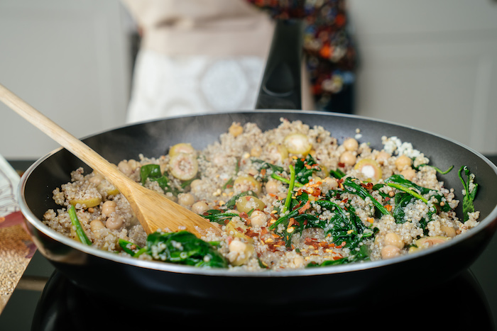 quinoa with olives, baby spinach, chilli powder, cooked in a pan, dinner ideas for two, wooden spatula