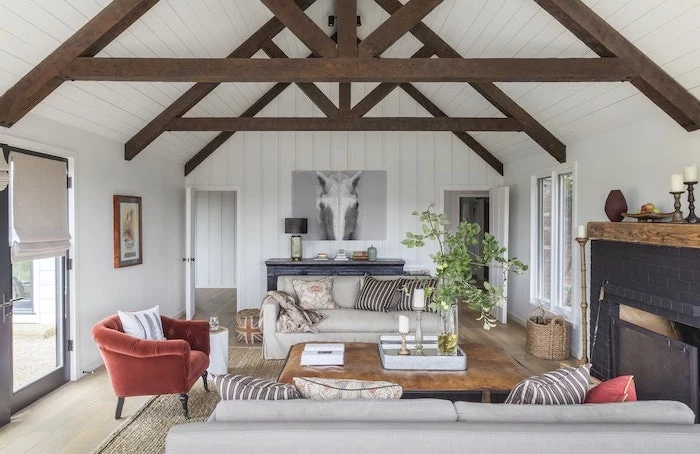 red velvet armchair, how to vault a ceiling, white wooden walls, wooden beams, white sofas, black brick fireplace