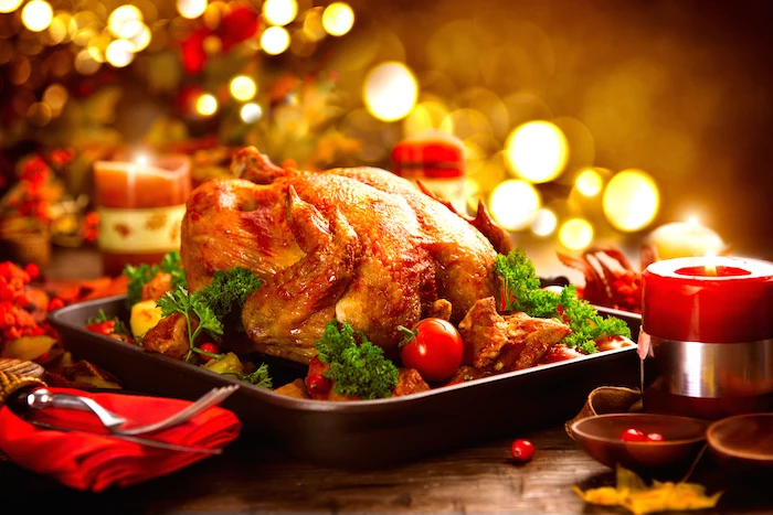 how to cook a thanksgiving turkey, wooden table, christmas candles, red cloth, roasted turkey, in a black pan
