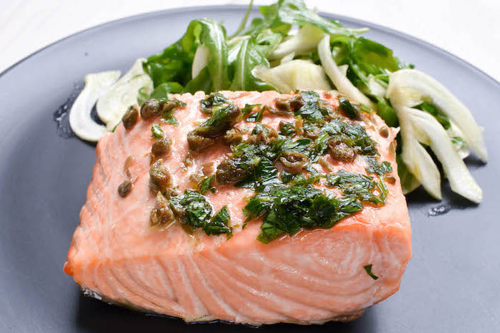simple meal plan to lose weight, salmon fillet, herbs sauce on top, salad on the side, black plate
