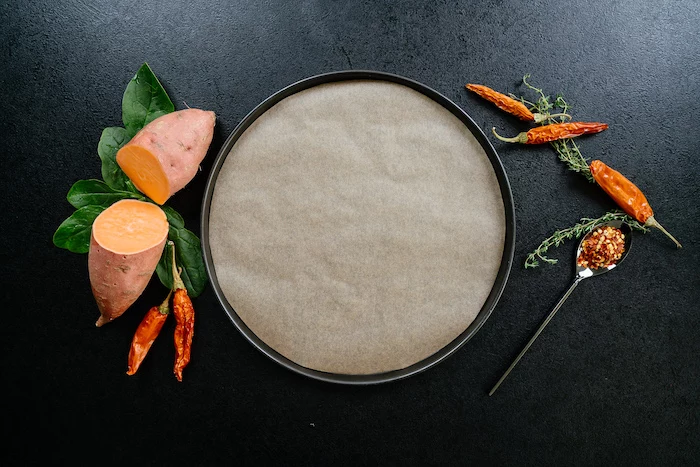 sheet pan, covered with paper, easy dinner recipes, chillis and thyme, sweet potato, cut in half, on black table
