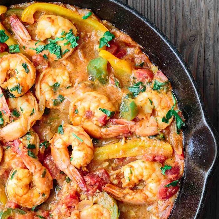 shrimp in creamy sauce, with peppers and tomatoes, parsley for garnish, in black skillet, healthy dinners for two