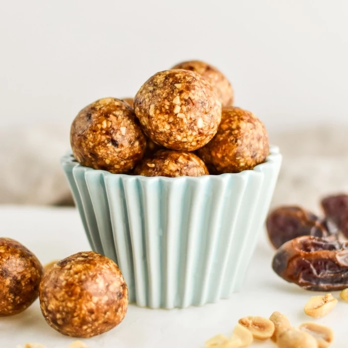 small blue bowl, chocolate peanut butter protein balls, dates and peanuts, scattered on the table