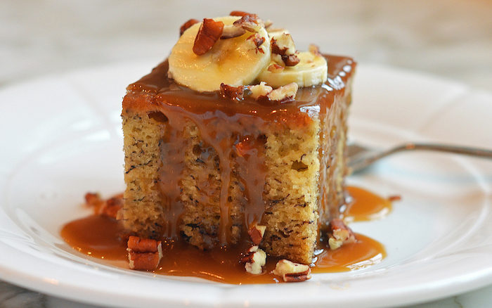 best thanksgiving pies, sticky toffee banana cake, crushed walnuts on top, caramel drizzle, white plate