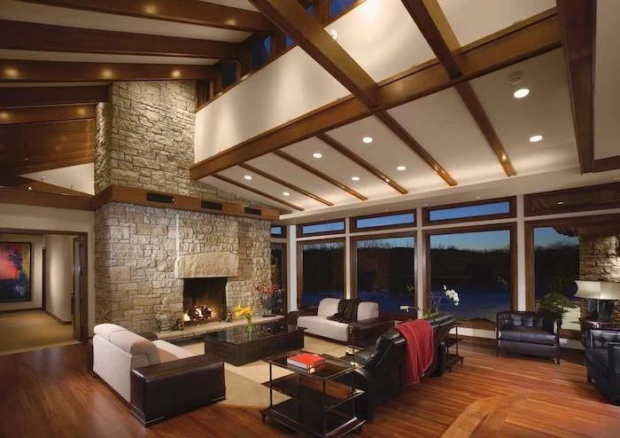 stone fireplace wall, black leather sofa and armchairs, wooden floor, how to vault a ceiling, wooden beams