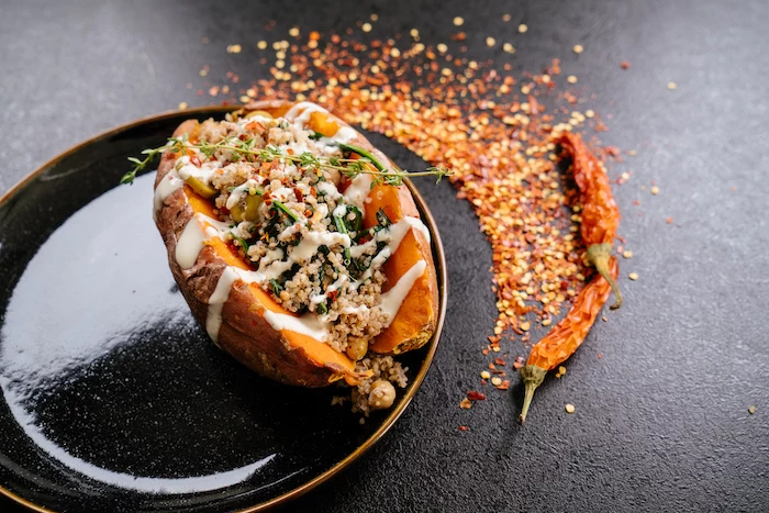 stuffed sweet potato, with sauce and thyme for garnish, in black plate, easy dinner ideas, chilli powder, on black table