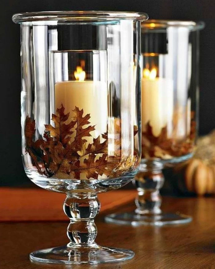 candles in glasses, fall leaves, inside large vases, thanksgiving home decorations, wooden table