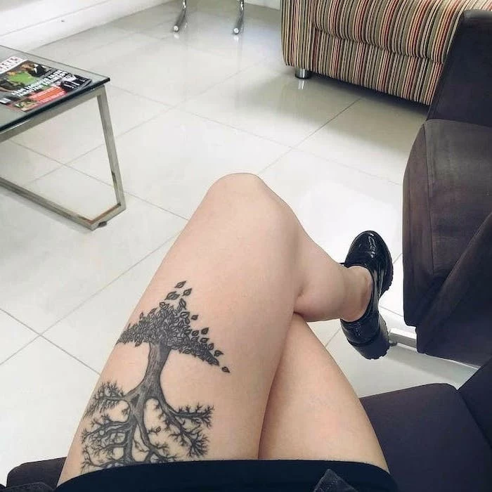 the tree of life, upper thigh tattoo, woman sitting on couch, wearing black shoes, white tiled floor