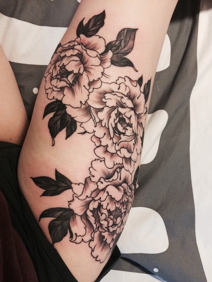 lion thigh tattoo, three flowers, black shorts, grey and white bed linen