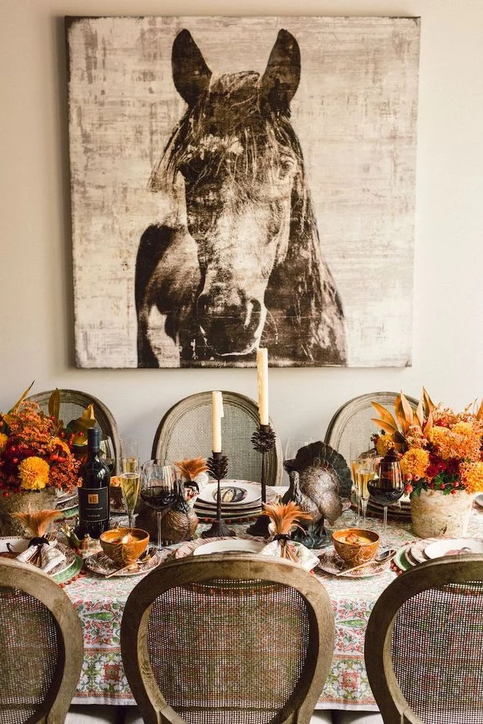 happy thanksgiving sign, wooden chairs, horse painting, flower bouquets, plate settings, turkey figurines, on the table