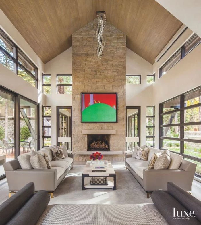 stone fireplace wall, grey sofas, tall windows, vaulted ceiling kitchen, wooden ceiling, white coffee table