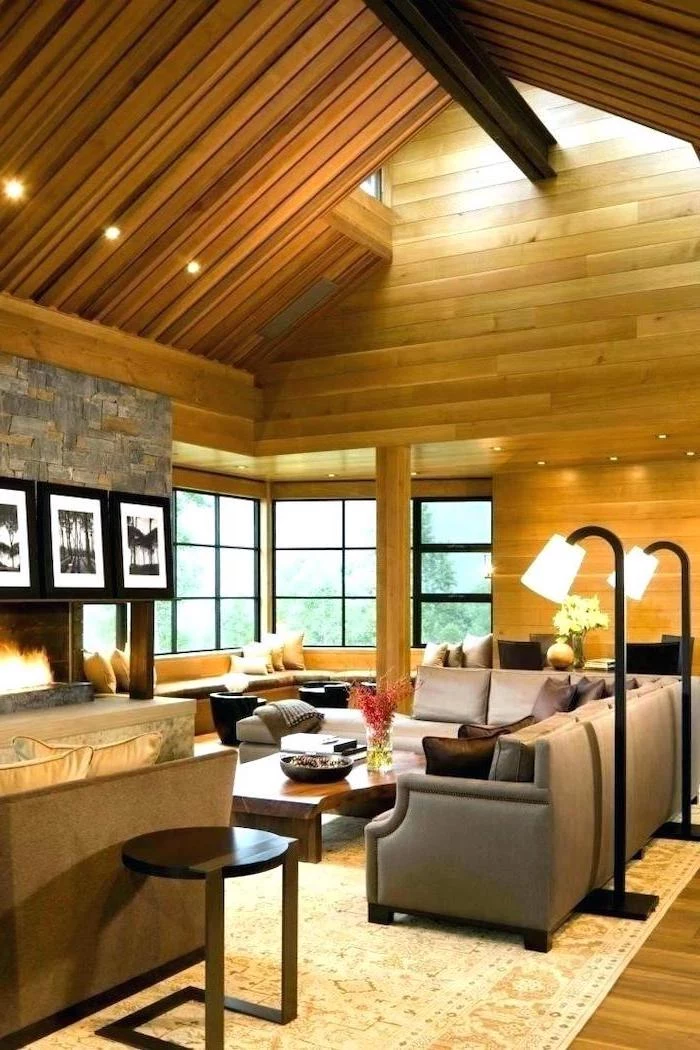 wooden walls and ceiling, grey corner sofa, vaulted ceiling kitchen, stone fireplace, wooden floor, white carpet