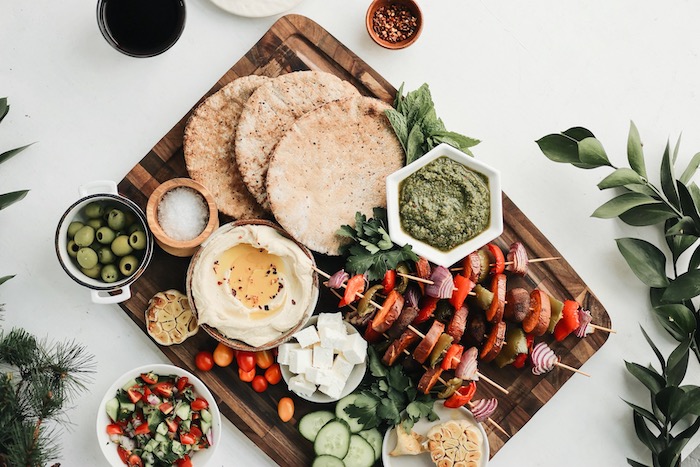 easy weeknight meals, wooden board, vegetable skewers, bowls with different dips, tortillas on top, cheese and olives